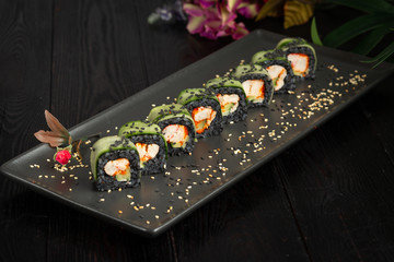 set of black rolls on a black rectangular plate on a dark wooden background