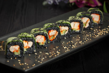 set of black rolls on a black rectangular plate on a dark wooden background