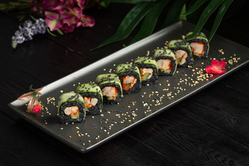 set of black rolls on a black rectangular plate on a dark wooden background