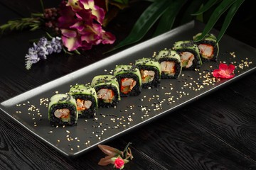 set of black rolls on a black rectangular plate on a dark wooden background