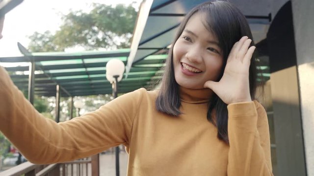 Cheerful beautiful young Asian backpacker blogger woman using smartphone taking selfie while traveling at downtown in Bangkok, Thailand. Lifestyle backpack tourist travel holiday concept.