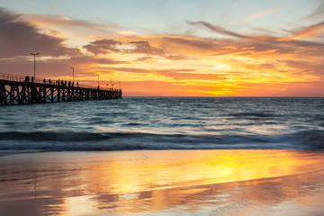 A beautiful sunset at Port Noarlunga with the jetty and sunset reflections on the sand at Port Noarlunga South Australia on 18th March 2019