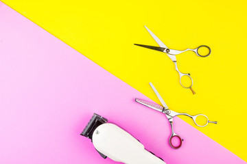 Stylish Professional Barber Scissors and White electric clippers on yellow and pink background. Hairdresser salon concept, Hairdressing Set. Haircut accessories. Copy space image, flat lay.