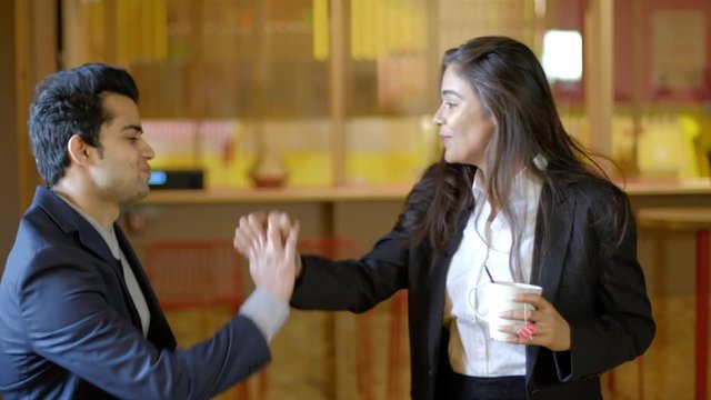 Young Indian colleagues workers facing each other discussion work as they smile and high five with hands to congratulate on the success and encourage each other to work harder and gain leadership 