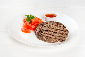 Grilled beefsteak on a white plate with tomatoes