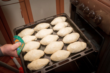 Freshly made pies lie on a baking sheet before cooking