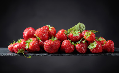 Ripe strawberries with green leaves on a black background.