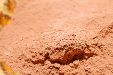 Dry cocoa powder poured into a brown ceramic plate