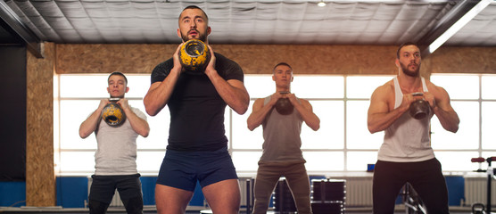 Male Athletes Training With Kettlebells in Crossfit Gym.