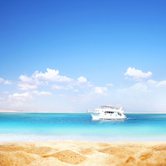 Summer background, nature of tropical golden beach with blue sky and white clouds. Golden sand beach close-up, turquoise water sea, white yacht, landscape. Copy space, summer vacation concept.