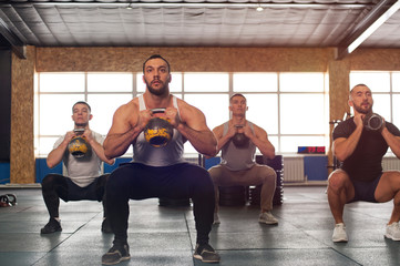 Fototapeta na wymiar Male Athletes Training With Kettlebells in Crossfit Gym.