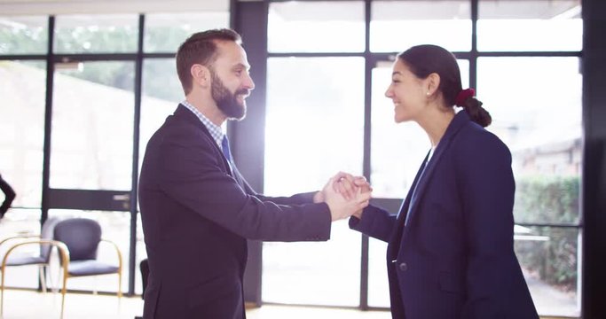 4K Success & positivity concept - business man & woman high-five each other in office. Slow motion.