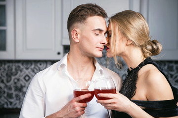 Couple man and woman young beautiful and happy in the kitchen with vine glasses