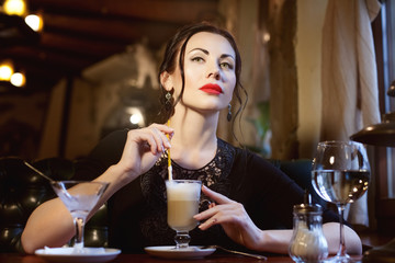 Woman at a table in a cafe drinking coffee.