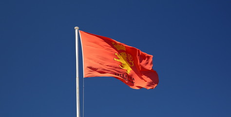 Flag of Valetta, capital city of Malta, waves on white pole, in background blue sky