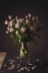Vase with beautiful roses on table against dark background
