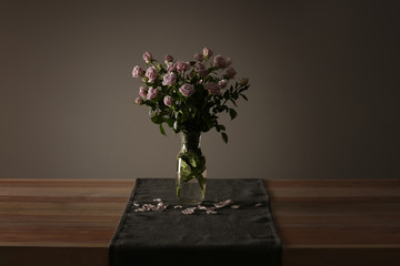 Vase with beautiful roses on table against grey background