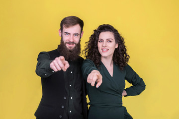 Cheerful young people pointing fingers at camera.