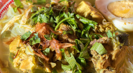 Soto Ayam is a chicken soup served with vegetables and rice - Image