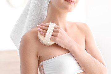 Beautiful young woman with massage brush at home