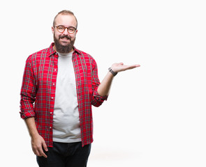 Young caucasian hipster man wearing glasses over isolated background smiling cheerful presenting and pointing with palm of hand looking at the camera.