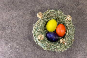 Handmade colorfull Easter eggs in selfmade grass nest on dark background