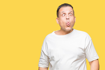 Middle age arab man wearig white t-shirt over isolated background making fish face with lips, crazy and comical gesture. Funny expression.