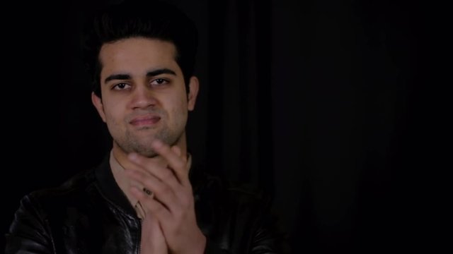 Young Indian man smug and confident looks at the camera with sarcasm and does a condescending slow clap of mock approval 