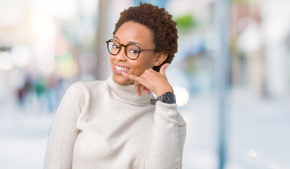 Young beautiful african american woman wearing glasses over isolated background smiling doing phone gesture with hand and fingers like talking on the telephone. Communicating concepts.