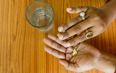 Self-treatment at home as per prescribed by doctor. Close up of a woman pouring medicine into her...