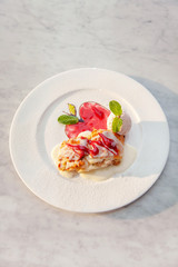 Apple strudel table raisins ice cream mint sultana berries sauce red green white plate close up top view
