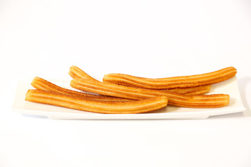 spanish fritters on a white dish with white background