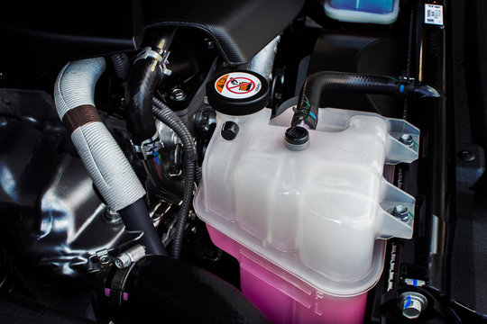 Coolant tank with a pink liquid antifreeze of a radiator system in car.