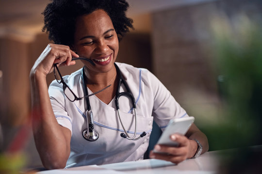 Happy African American Female Doctor Text Messaging On Smart Phone.