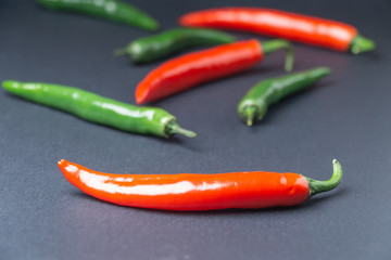 Green and red chili peppers on black background. Hot spicy food symbol.