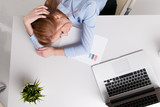 Young office girl sitting at her workplace feeling bad. Woman has a headache. Looking tired