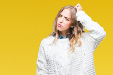 Beautiful young blonde woman wearing winter sweater over isolated background confuse and wonder about question. Uncertain with doubt, thinking with hand on head. Pensive concept.