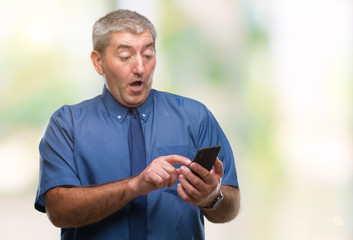 Handsome senior man texting sending message using smartphone over isolated background scared in shock with a surprise face, afraid and excited with fear expression