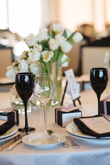 Wedding decor. Reception. Table number 1 on black wooden stand. Glasses and cutlery on side. Steampunk style