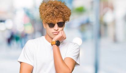 Young handsome man with afro hair wearing sunglasses thinking looking tired and bored with depression problems with crossed arms.