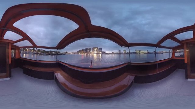 360 VR Video. Timelapse shot of boat traveling on Amsterdam canals at night. Touristic water trip to observe the capital of Netherlands
