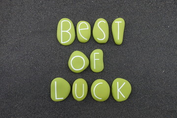 Best of luck text composed with green colored stones over black volcanic sand