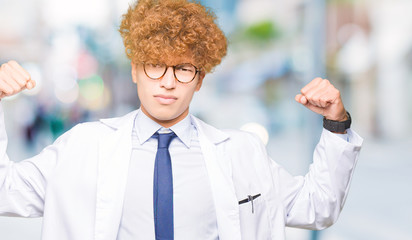 Young handsome scientist man wearing glasses showing arms muscles smiling proud. Fitness concept.