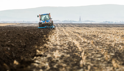 Fototapeta premium Farmer plowing stubble field