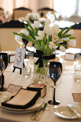 Wedding decor. Reception. Table number 1 on black wooden stand. Glasses and cutlery on side. Steampunk style