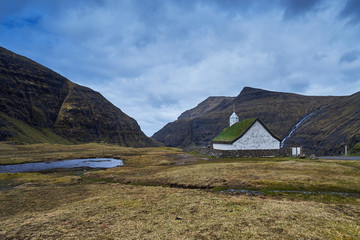 Fototapeta na wymiar Mediaeval church with grass or turf roof in village Saksun or danish Saksen near the northwest coast of the Faroese island of Streymoy, in Sunda Municipality. Picture is taken in cloudy spring morning