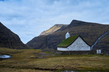 Fototapeta na wymiar Mediaeval church with grass or turf roof in village Saksun or danish Saksen near the northwest coast of the Faroese island of Streymoy, in Sunda Municipality. Picture is taken in cloudy spring morning