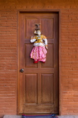 Pretty traditional style Burmese string puppet decoration on copper coloured door set in brick...