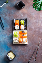 Traditional Japanese food- sushi, rolls, chopsticks, soy sauce on duotone slate background. Sushi menu. Top view copy space