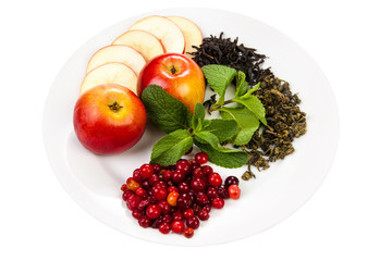 Composition. Black and green tea, apples, berries, fresh mint, on a white plate. Isolated